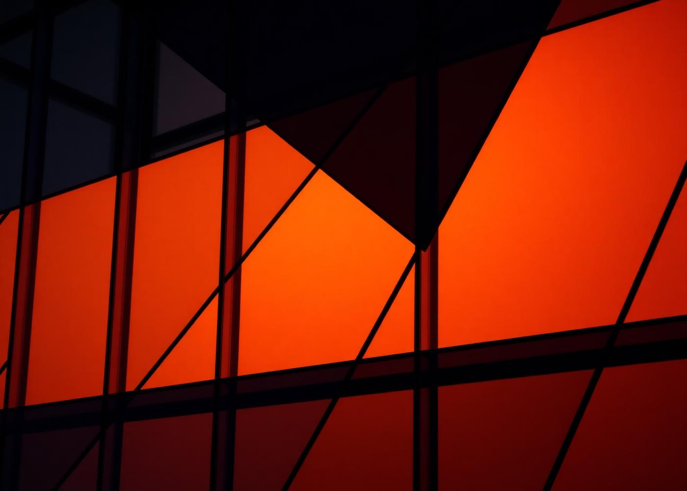 Abstract composition of overlapping glass panels lit in amber and deep shadow